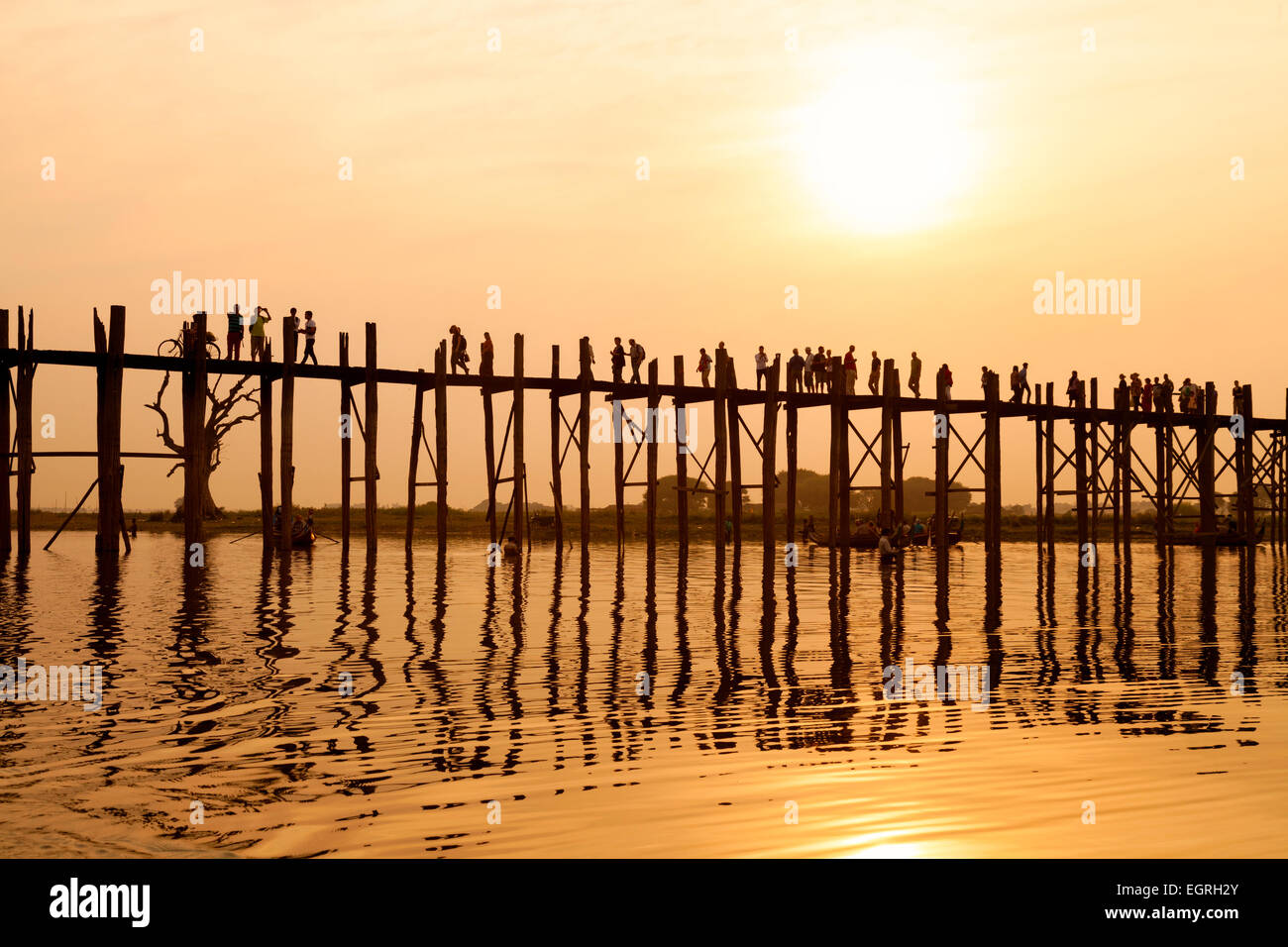 People crossing the U Bein bridge over the Taungthaman Lake at sunset ...