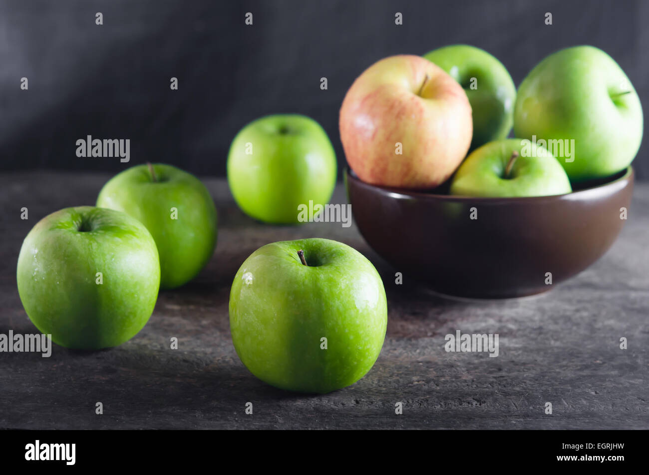 Bowl of green apples and apple over wooden board Stock Photo