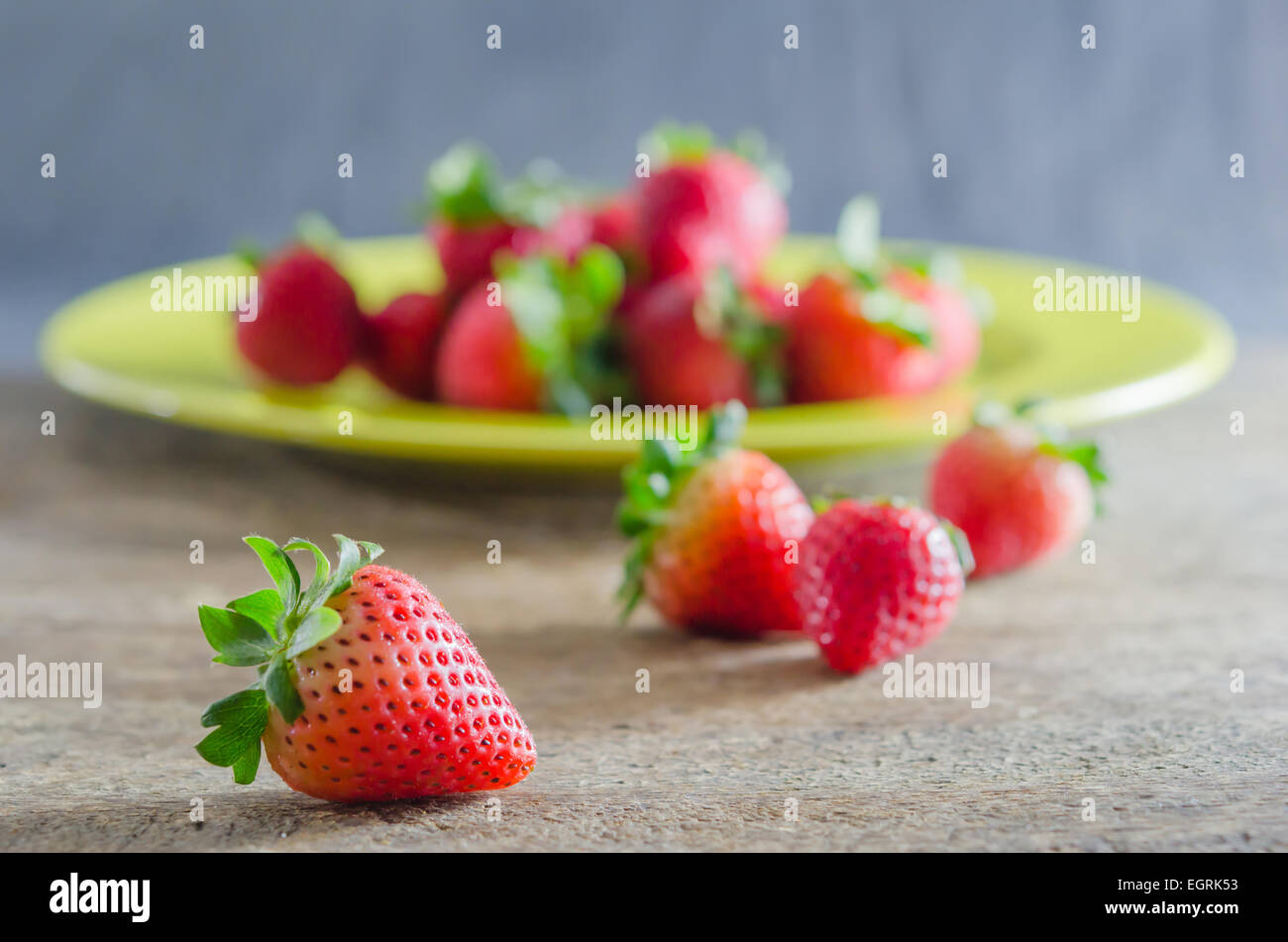 still life of fresh red strawberries on dish over wooden background ...