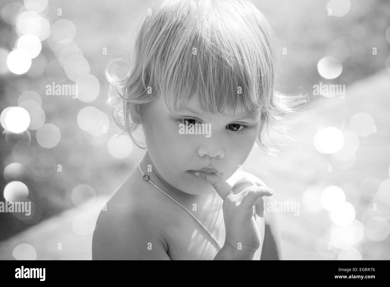 Outdoor closeup portrait of cute thinking Caucasian blond baby girl. Vintage toned photo with instagram retro toning filter effe Stock Photo