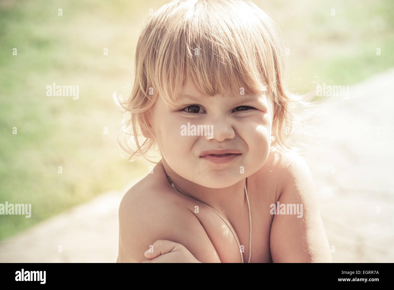 Outdoor close-up portrait of funny smiling Caucasian blond baby girl ...