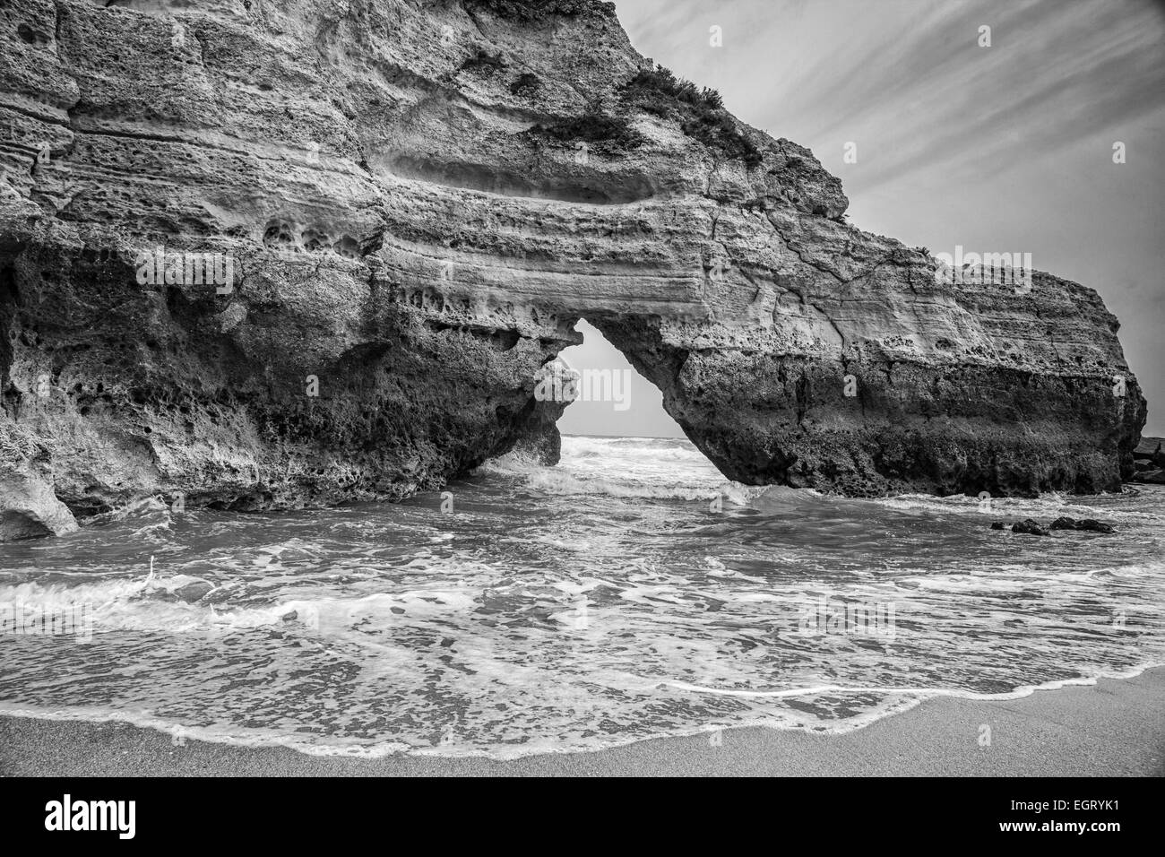 the rugged rocks of the Praia de Rocha Beach near Portimao Portugal, ocean waves and streaky clouds. Stock Photo