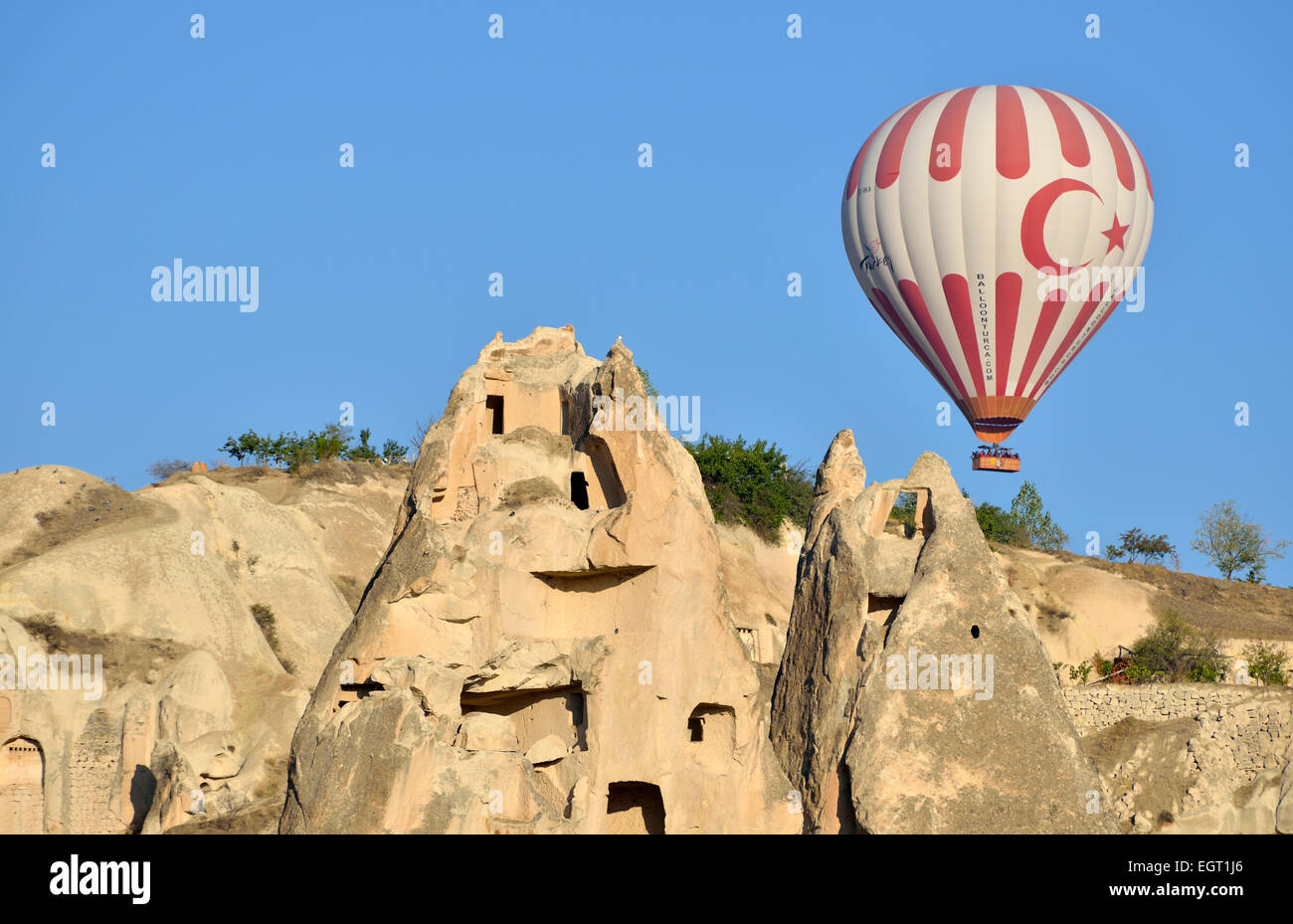 Hot air balloon flying over tufa rock formations and ancient cave dwellings, Goreme, Cappadocia, Turkey Stock Photo