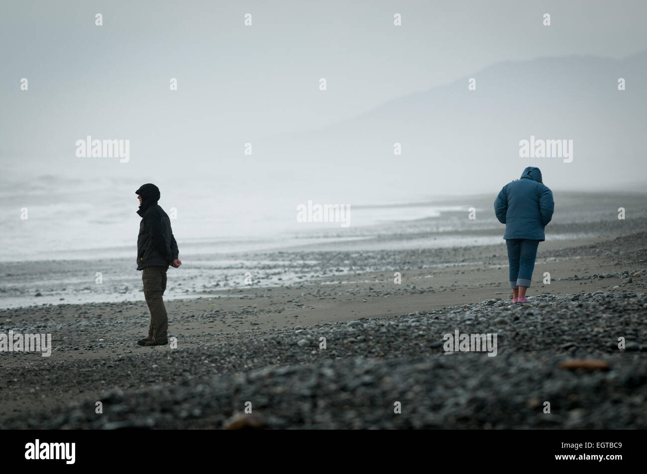 A couple walk during stormy weather on South Beach, Greymouth, West Coast, South Island, New Zealand. Stock Photo