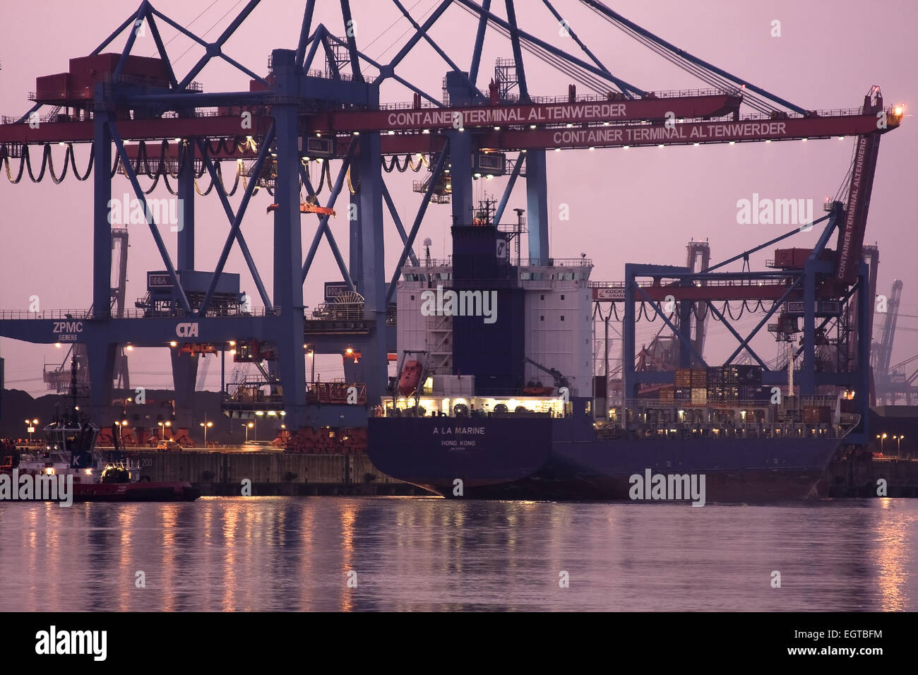Containererschip is charged at dusk, at Container Terminal Altenwerder, Hamburg harbor, Germany Stock Photo