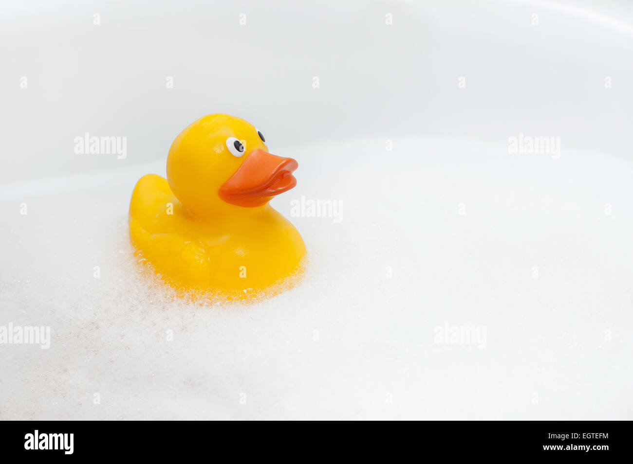 Cute rubber duck floating in suds isolated with copy space Stock Photo