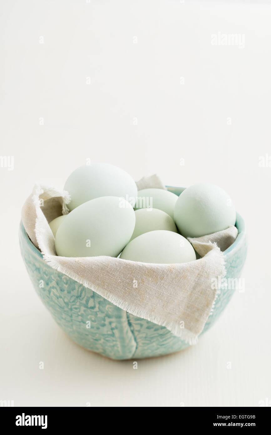 Fresh light green eggs from Easter egger chicken in a light blue bowl