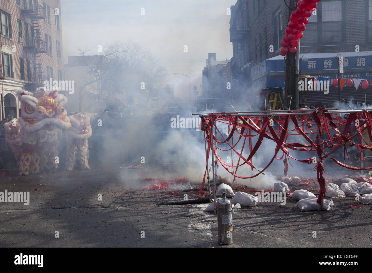 Street becomes enveloped in smoke during the firecracker ceremony on Chinese New Year in the Chinatown section of Brooklyn, NY. Chinese people from the Chinatown/Sunset Park neighborhood of Brooklyn, NY celebrate Chinese New Year  with a parade and festival bringing in The Year Of The Ram, 2015 Stock Photo