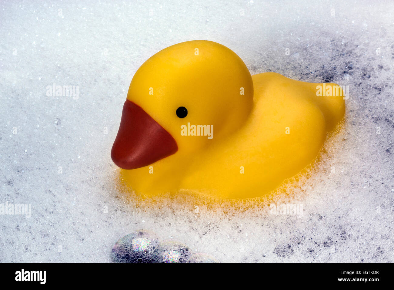A rubber duck floating in bubbles in a bathtub. Stock Photo