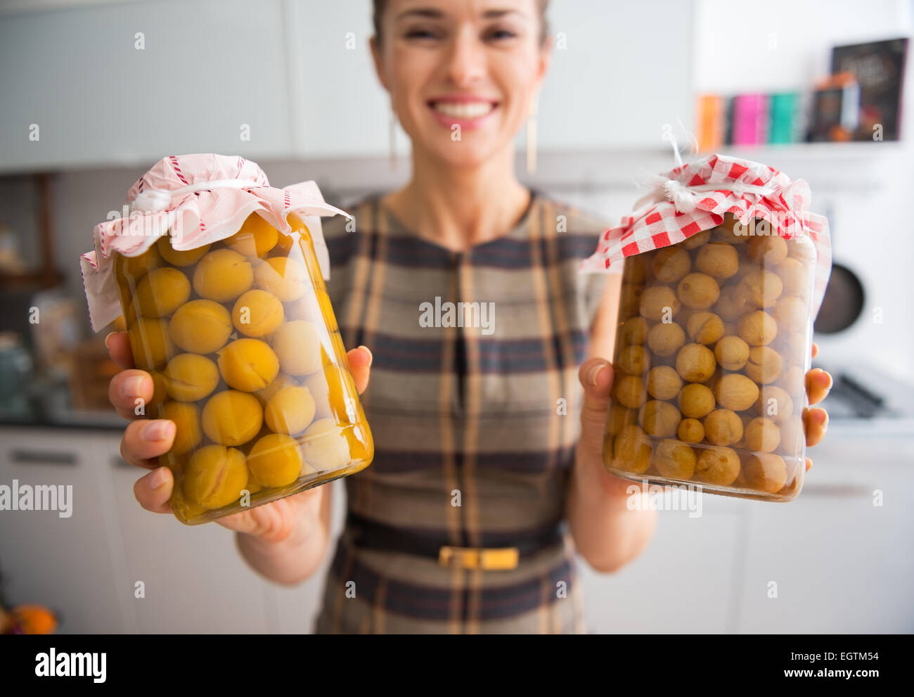 Closeup on young housewife showing jars with homemade gooseberry and plum compote Stock Photo