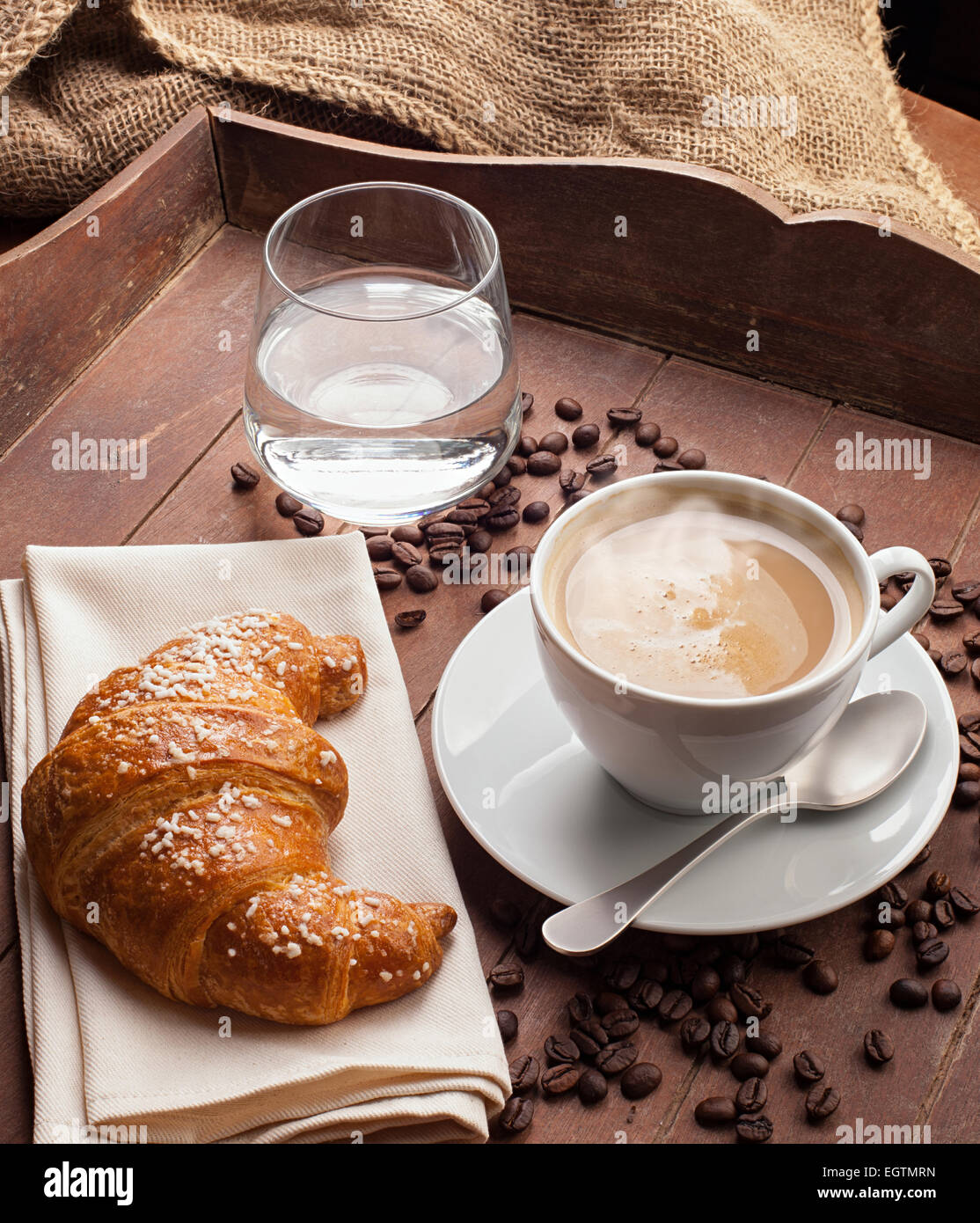 Cappuccino with croissant and glass of water in the tray of brown wood  Stock Photo - Alamy