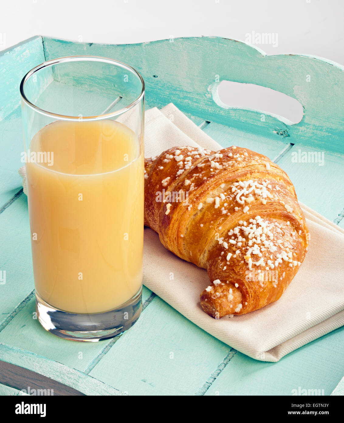 Croissant and pear juice on light blue tray. Stock Photo