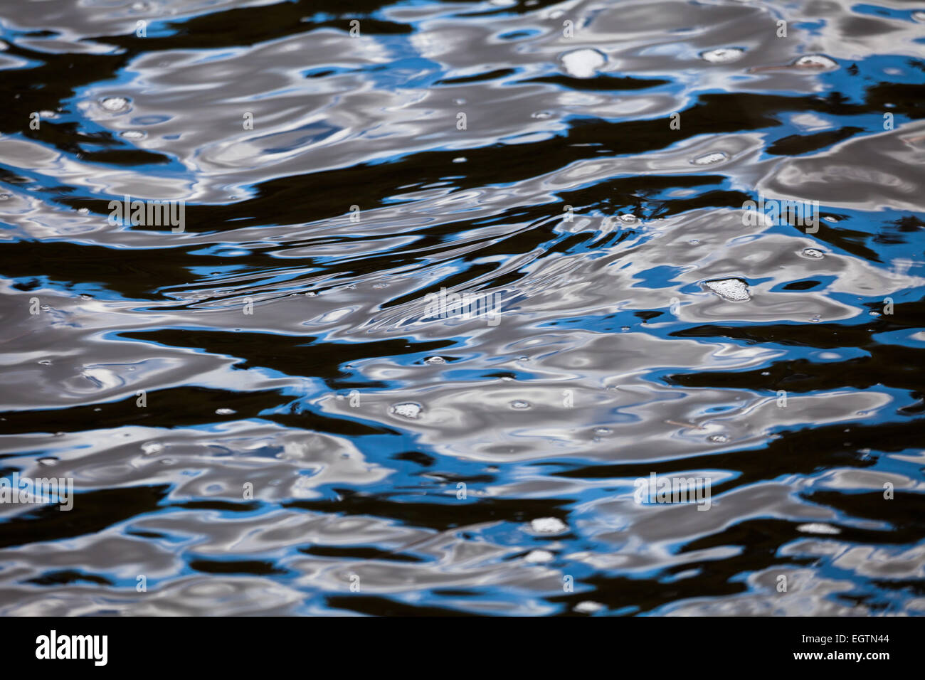 Water surface abstractions in the lake Vansjø, Østfold fylke, Norway. The blue skies are reflected in the moving waves. Stock Photo