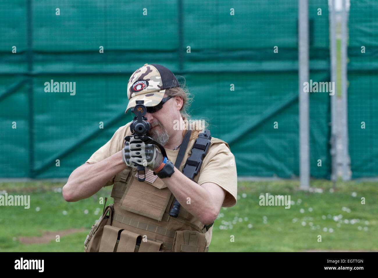 Reenactor in the military style uniform  of a private security firm points a reproduction firearm at the camera Stock Photo