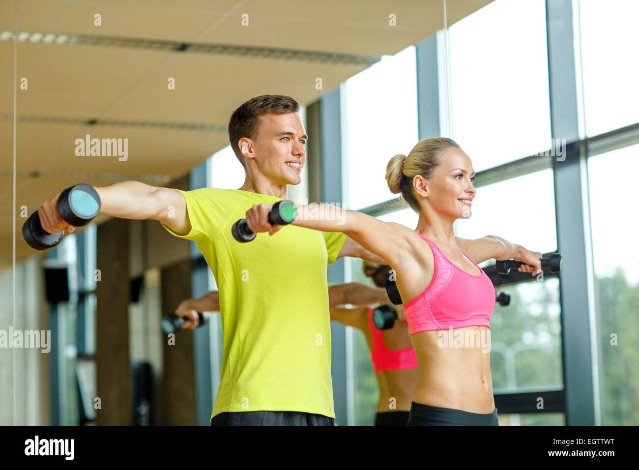 smiling man and woman with dumbbells in gym Stock Photo - Alamy