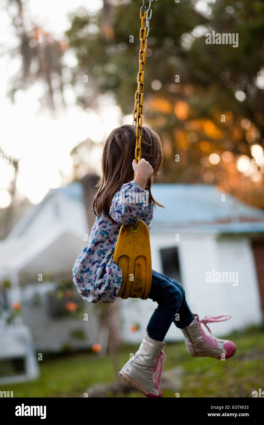 A girl sits on a backyard swing. Stock Photo