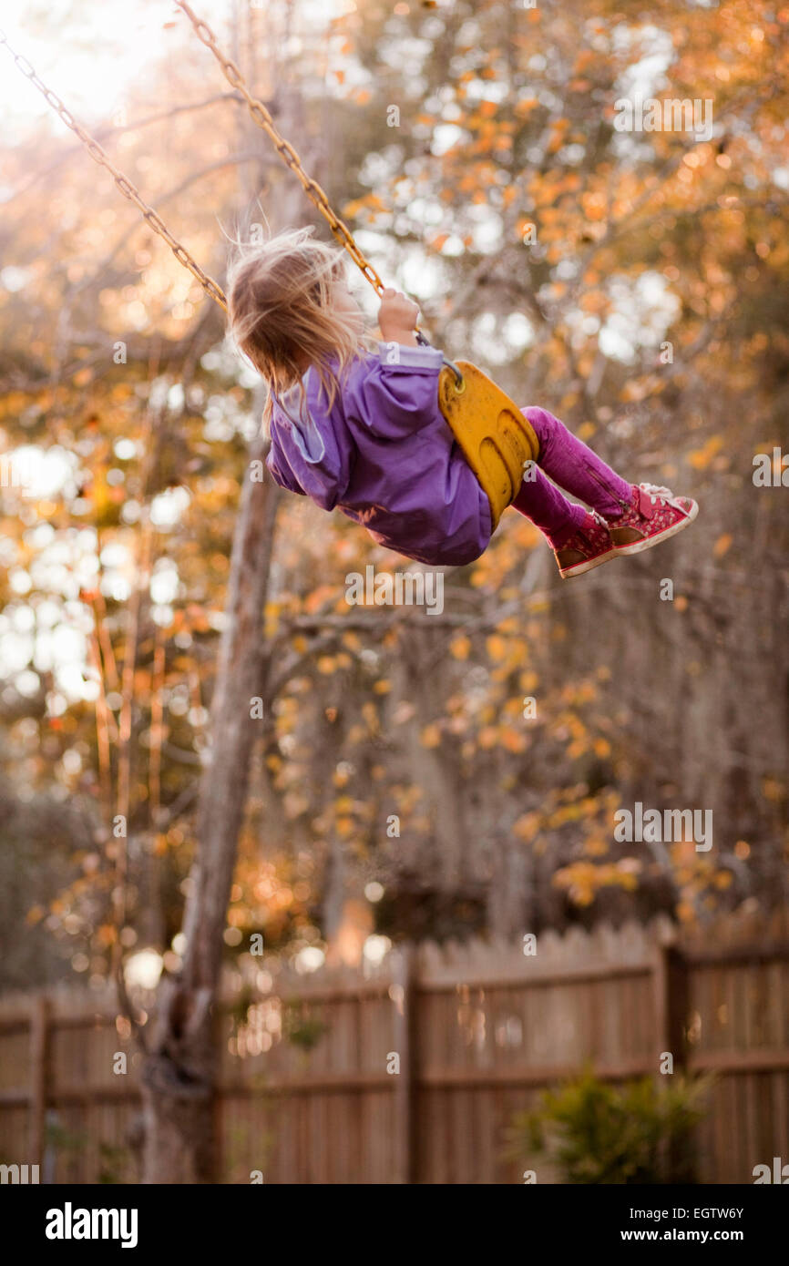 A girl swinging on a backyard swing. Stock Photo