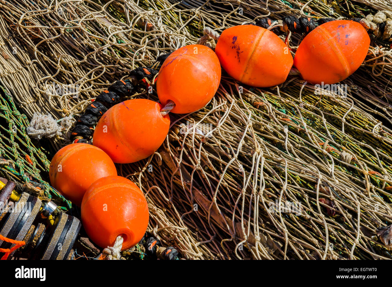 A pile of grey fishing nets and on top several orange buoys in the harbour of Urk, Flevoland, The Netherlands. Stock Photo