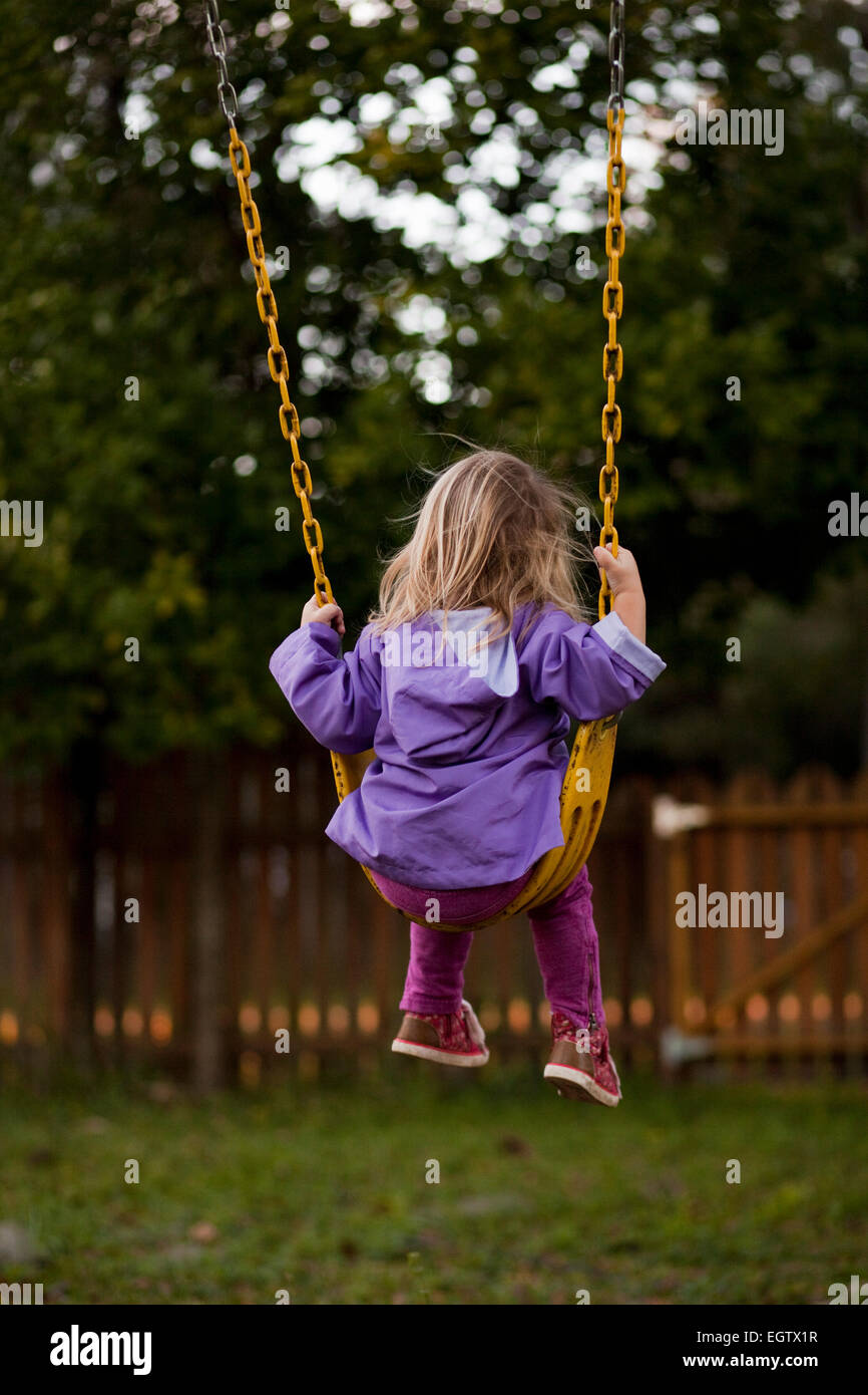 A toddler girl sits on a swing. Stock Photo