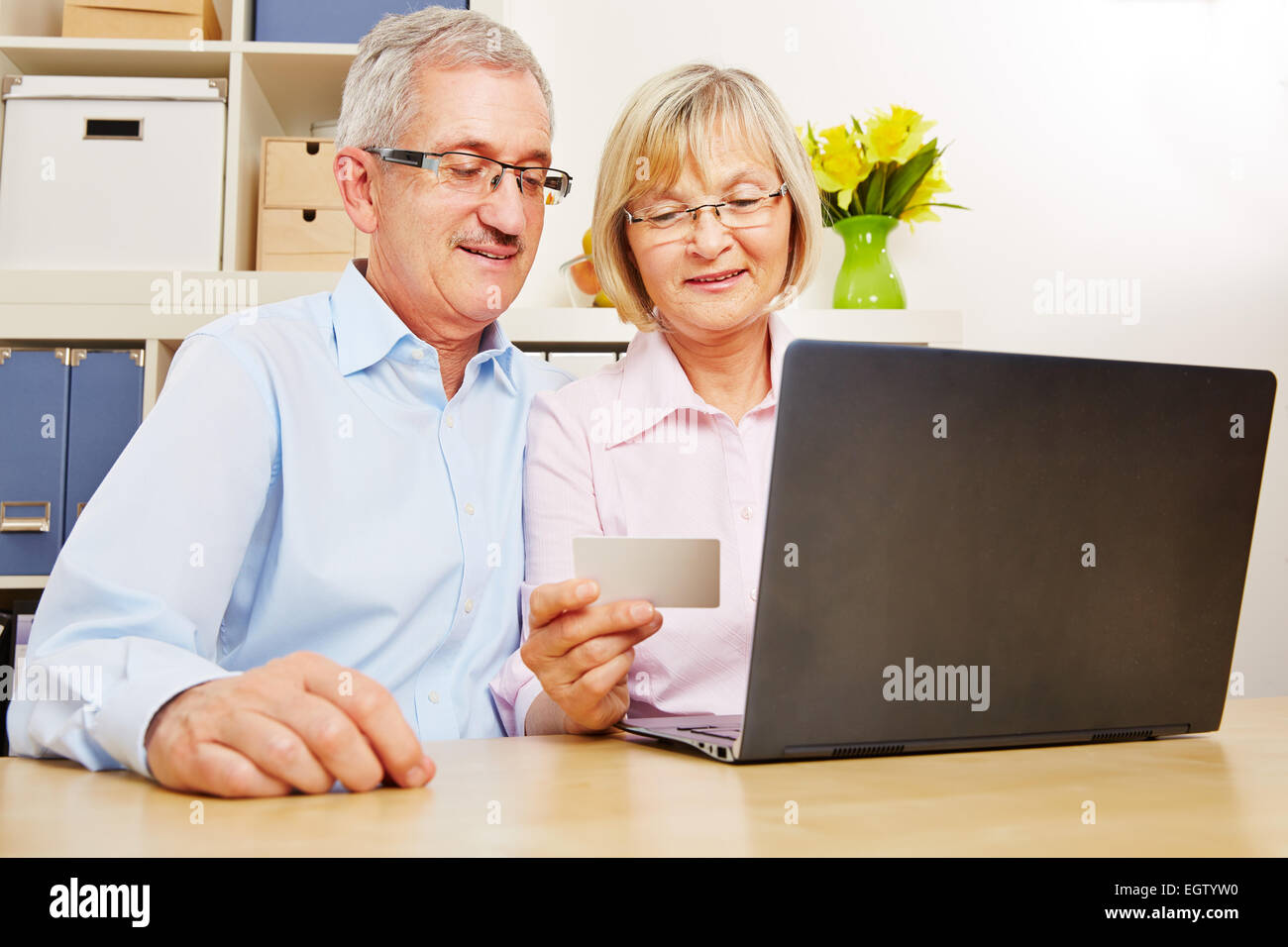 Happy senior couple doing online banking at laptop computer with credit card Stock Photo