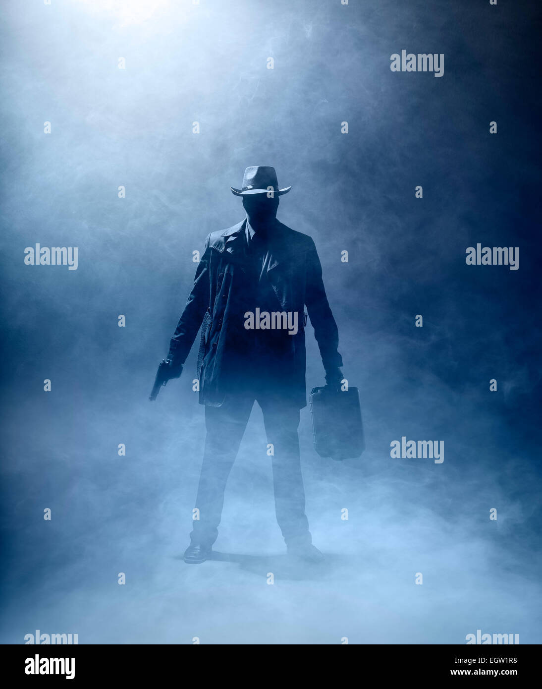 Faceles man with a gun and a briefcase standing in the fog. Stock Photo