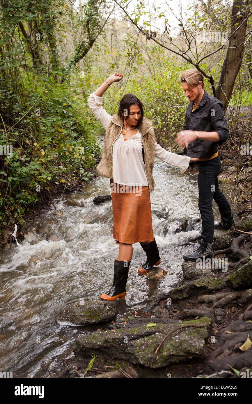 Woman waling across creek with man behind her. Stock Photo