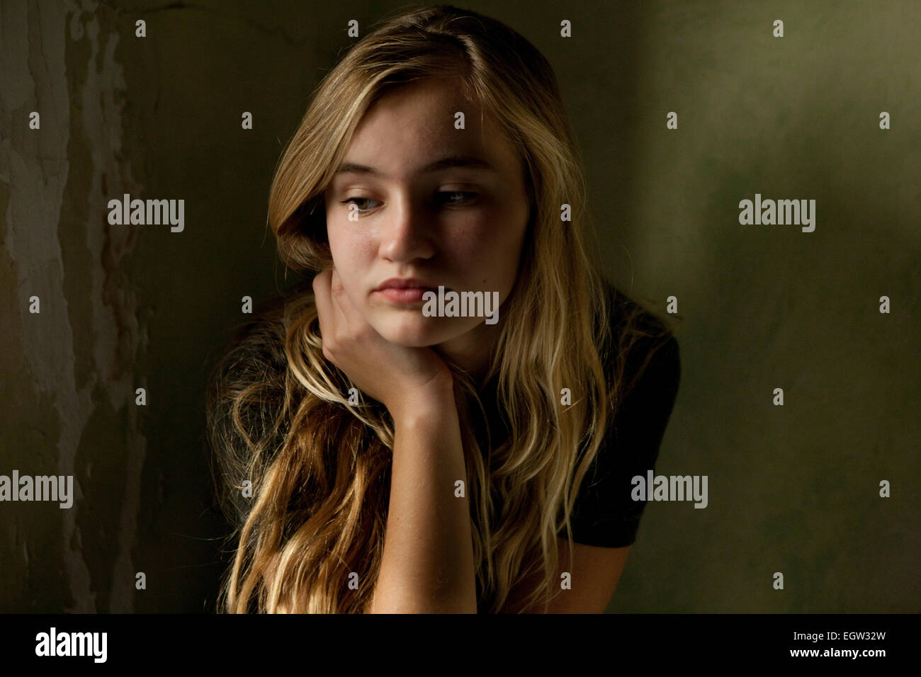 Teen girl resting her chin in hand looking worried Stock Photo - Alamy