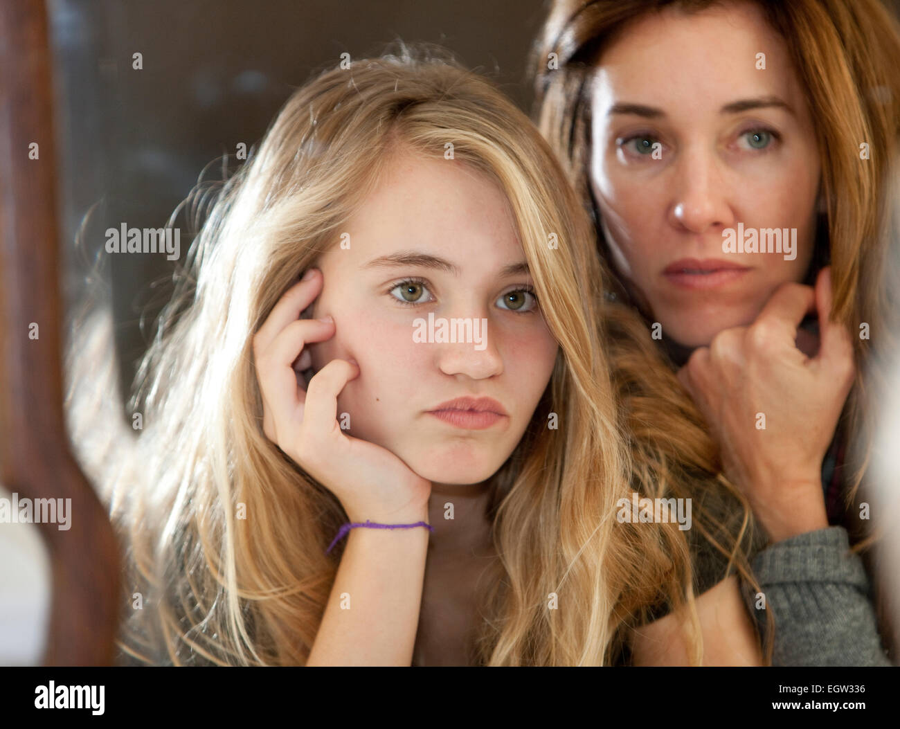 Mother and teen daughter resting their chins in hands. Stock Photo