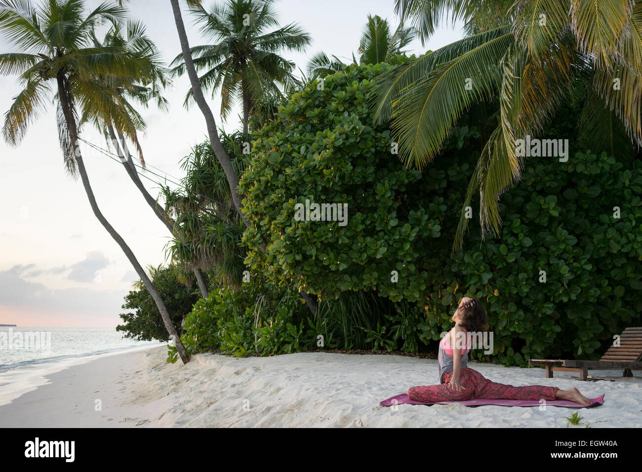 Woman doing yoga on beach in the Maldives. Stock Photo