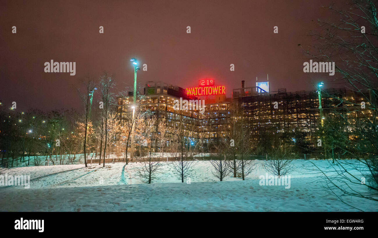 A building with a Watchtower neon sign, showing the temperature and date, seen from Brooklyn Bridge Park in the Brooklyn Heights neighborhood of Brooklyn in New York on Tuesday, February 24, 2015.  Despite the Watchtower being a Jehovah Witness publication the church has sold off most of their extensive real estate holdings in Brooklyn Heights and they are on the way to being condos or tech hubs.  © Richard B. Levine) Stock Photo