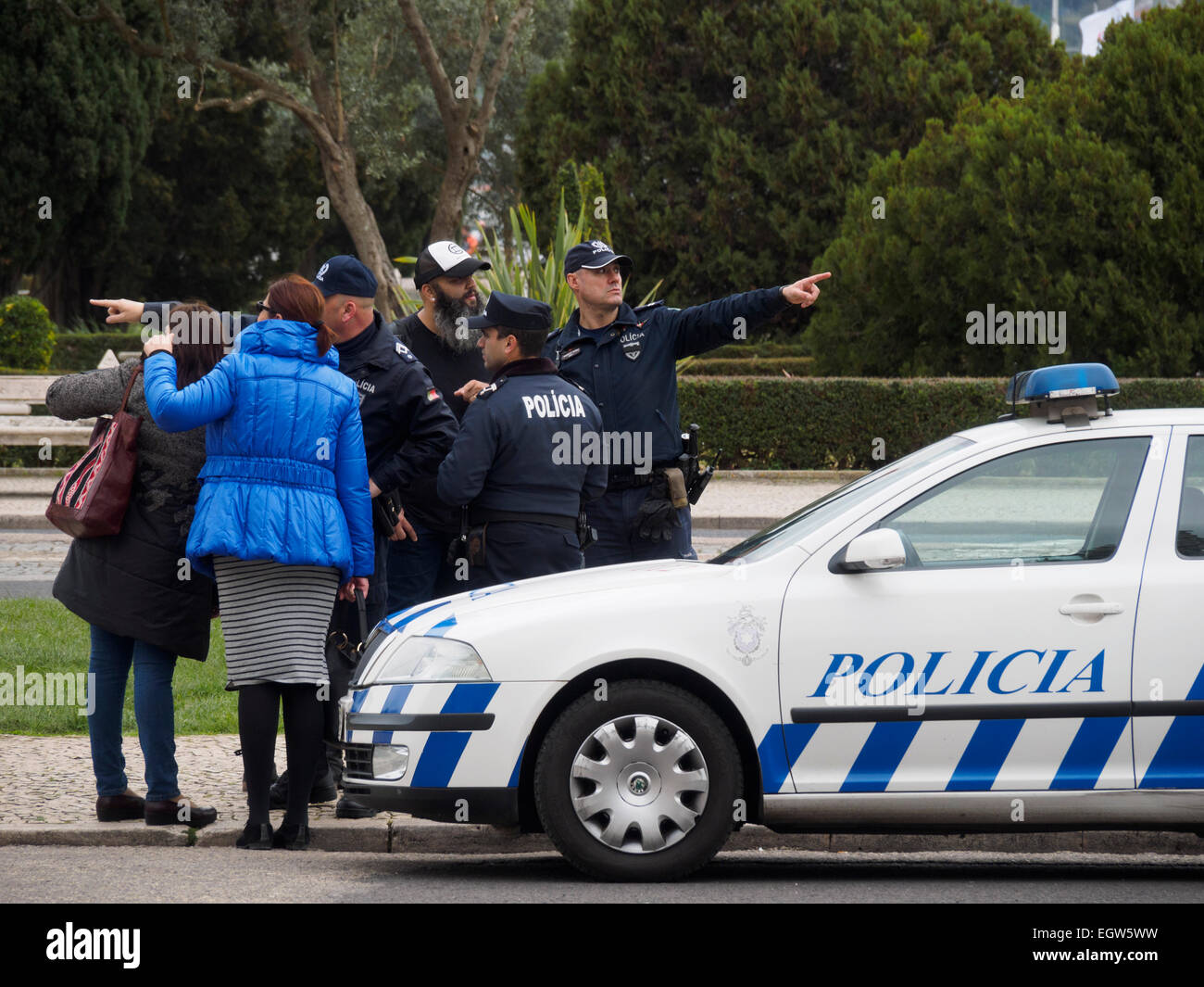 Lost tourists asking portuguese police officers for directions next to a police car in Lisbon, Portugal Stock Photo