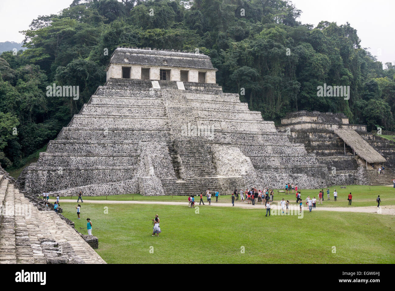 visitors wander around base of stepped pyramid structure Temple of the Inscriptions seen from steps of Palacio Palace Palenque Stock Photo