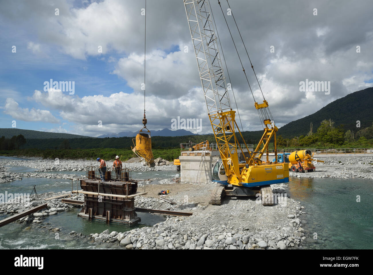 Builders pour concrete into the foundations of a concrete bridge over a small river in Westland, New Zealand Stock Photo