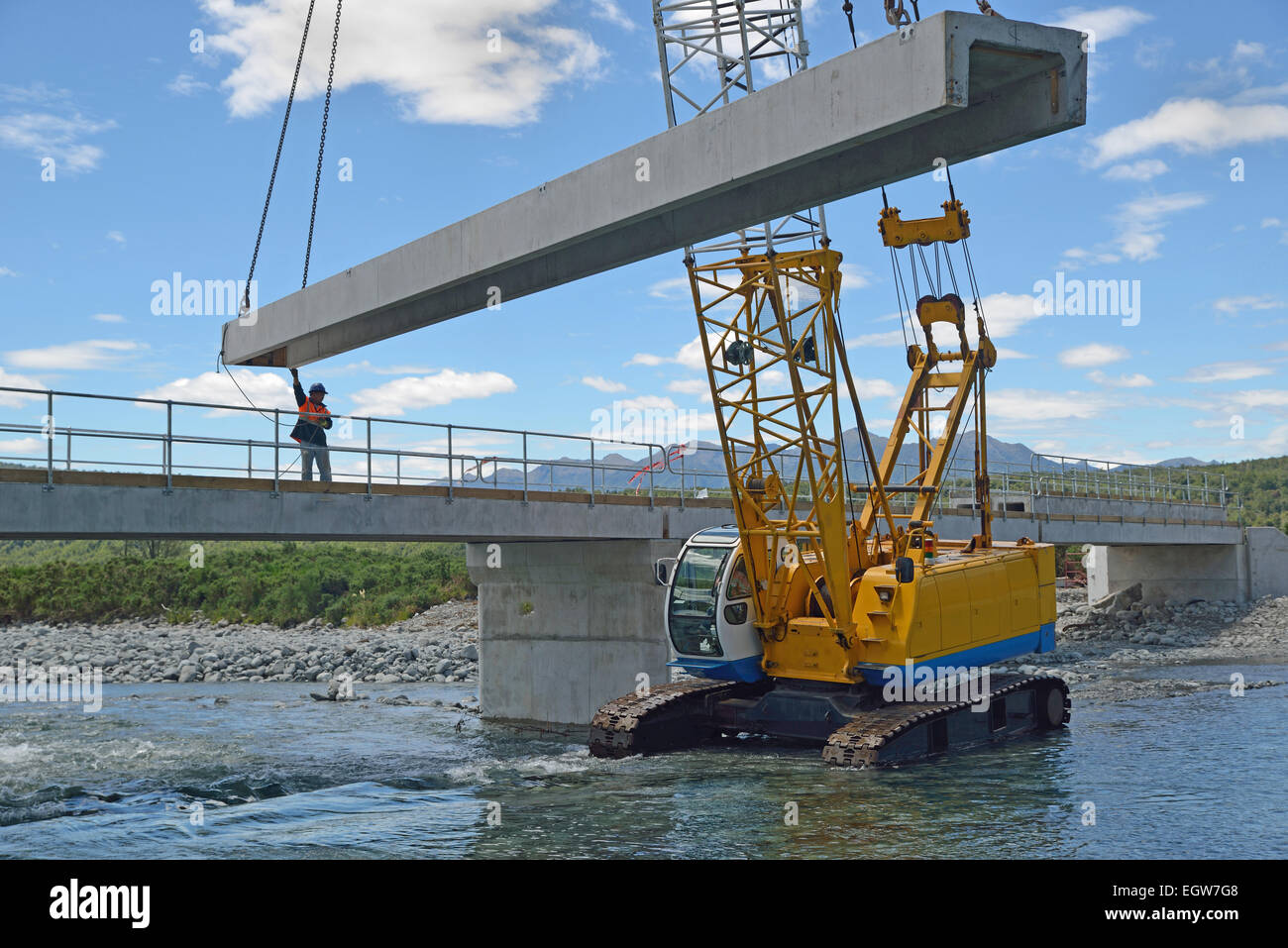 Builders construct a concrete bridge over a small river in Westland, New Zealand Stock Photo