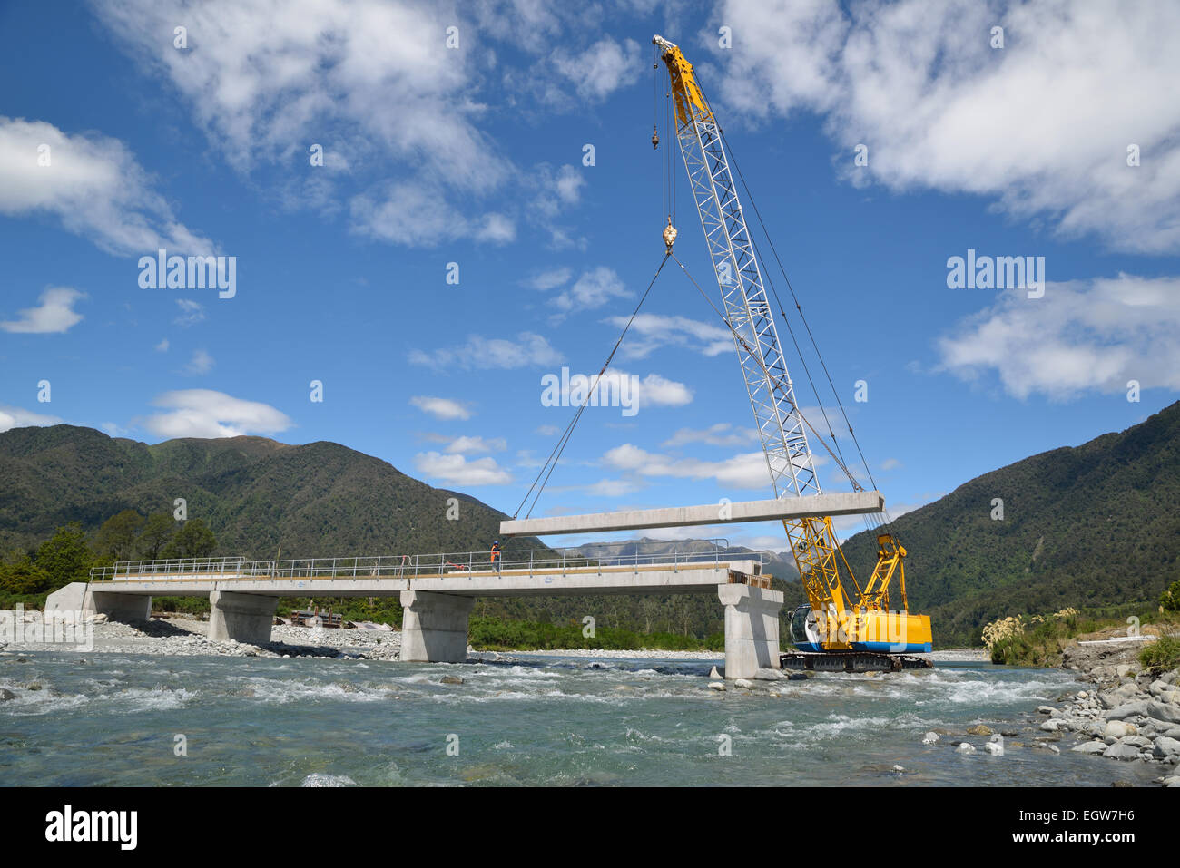 Builders construct a concrete bridge over a small river in Westland, New Zealand Stock Photo