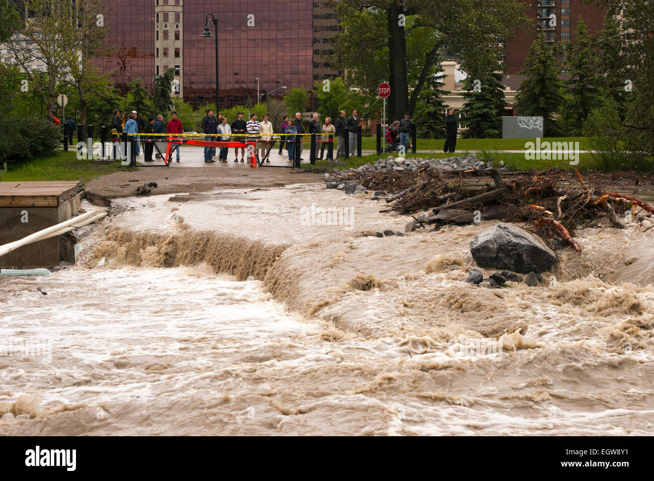 People watching floodwaters washing away pedestrian bridge to Prince's Island Park  in downtown Calgary Stock Photo