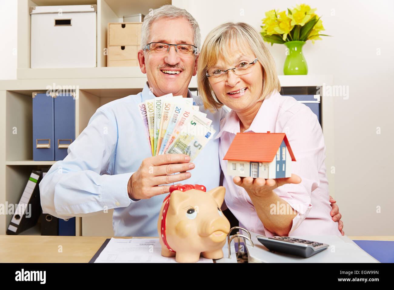 Happy senior couple with Euro money bills and house and piggy bank ...