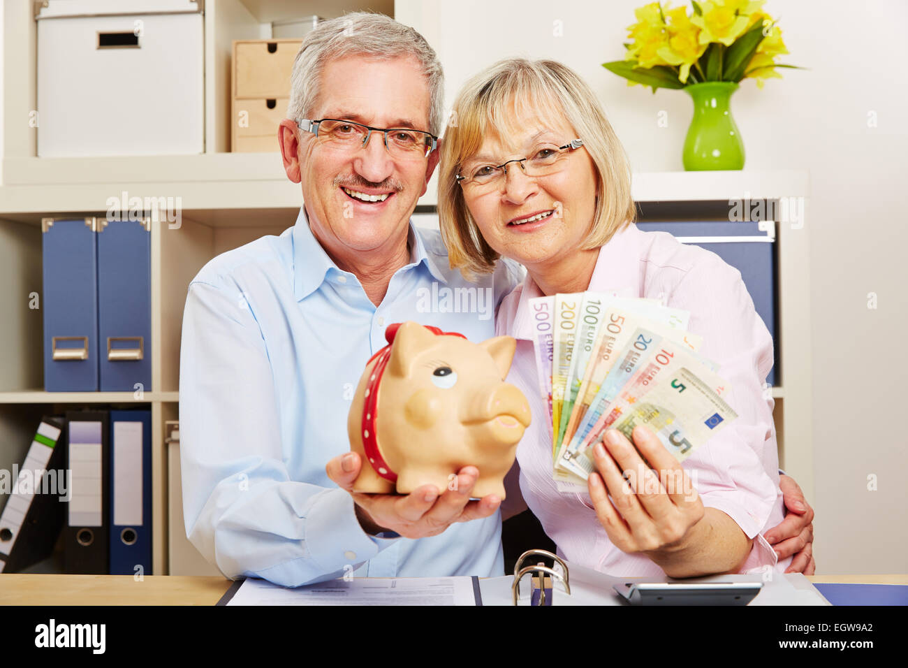 Smiling senior couple with euro money bills and a piggy bank Stock Photo