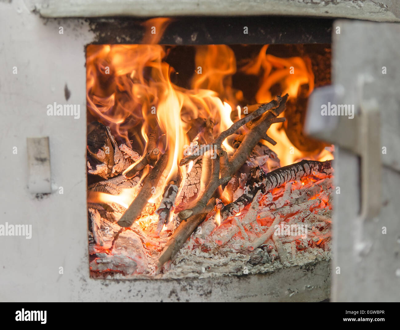 Distillation still Pot chamber fire-place burning wood branches with open door, detail with selective focus Stock Photo