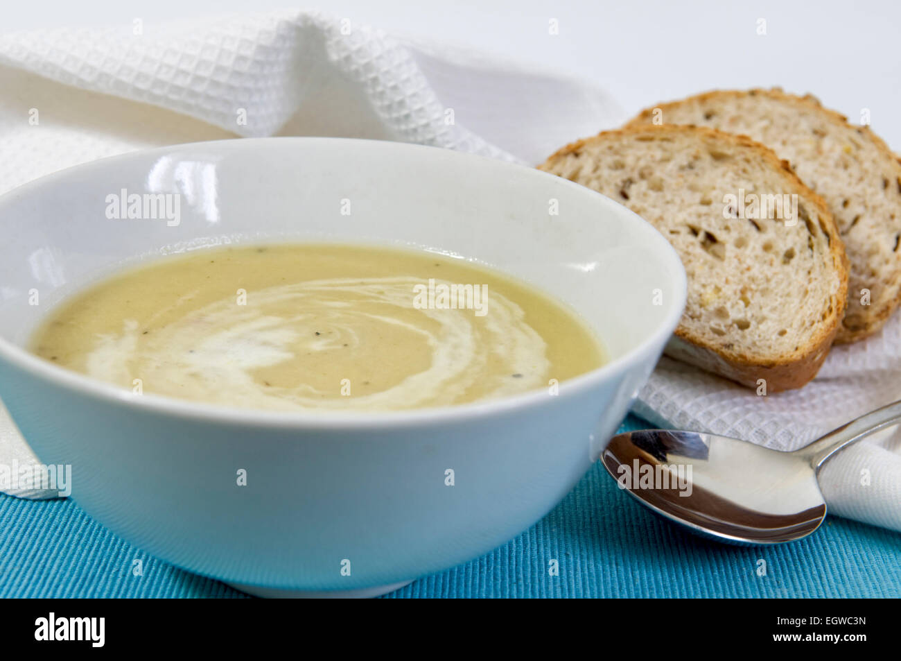 Homemade leek and potato soup in bowl with fresh bread on the side and swirl of cream on top Stock Photo