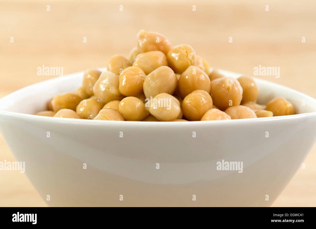 Close up of chick peas in white bowl on wooden table Stock Photo