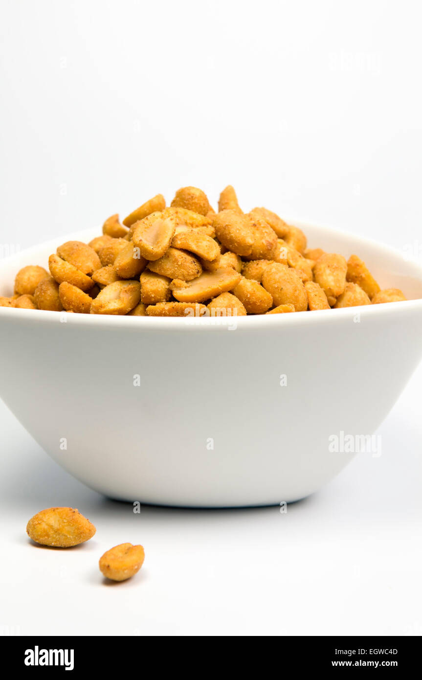 Spicy chilli coated peanuts in white bowl on white background Stock Photo