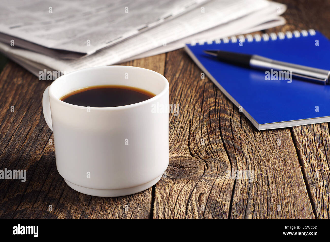 Cup of coffee, newspaper and notepad on old wooden table Stock Photo