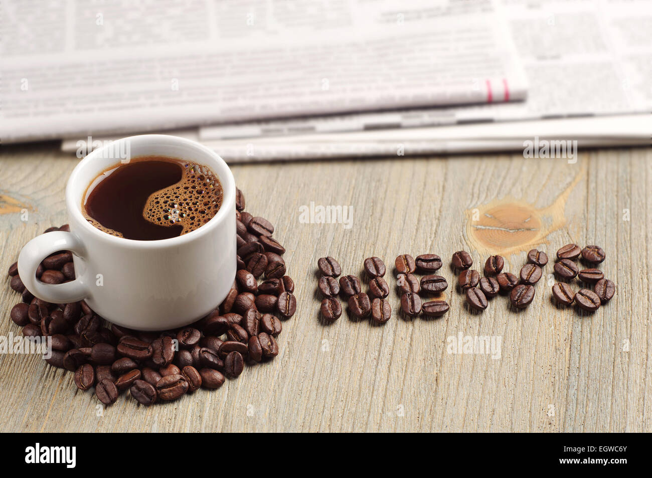 Coffee cup, newspaper and the word news on wooden table Stock Photo