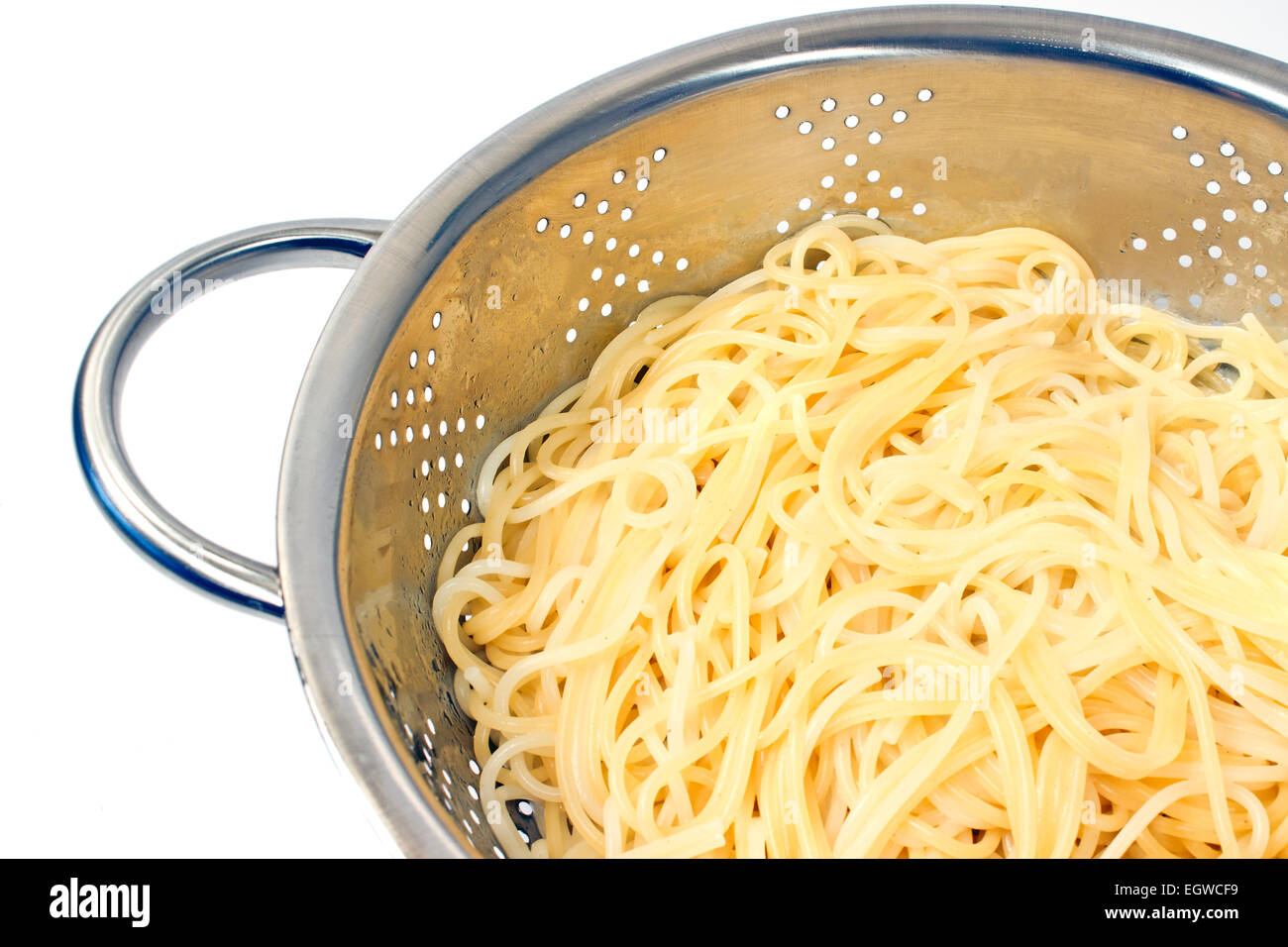 Fresh cooked spaghetti in stainless strainer on white Stock Photo