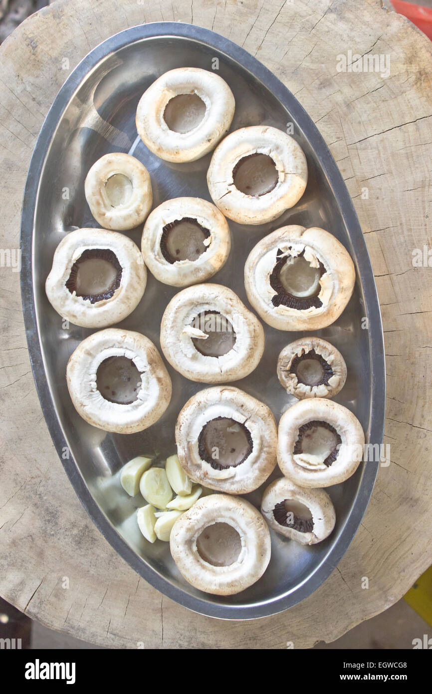 Fresh mushrooms in a metal bowl on stump Stock Photo