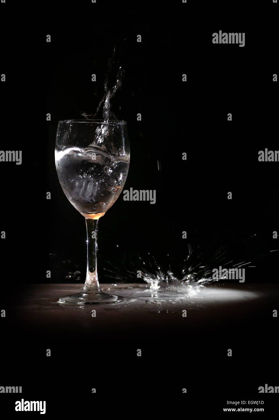 Wine glass explodes water in spotlight, splashes a puddle Stock Photo ...