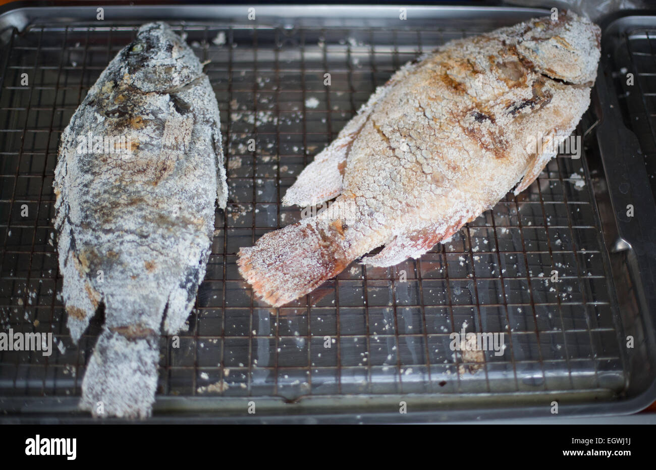 Two grilled and salted Tilapia fish on a metal gill rack, Talat Phlu ...