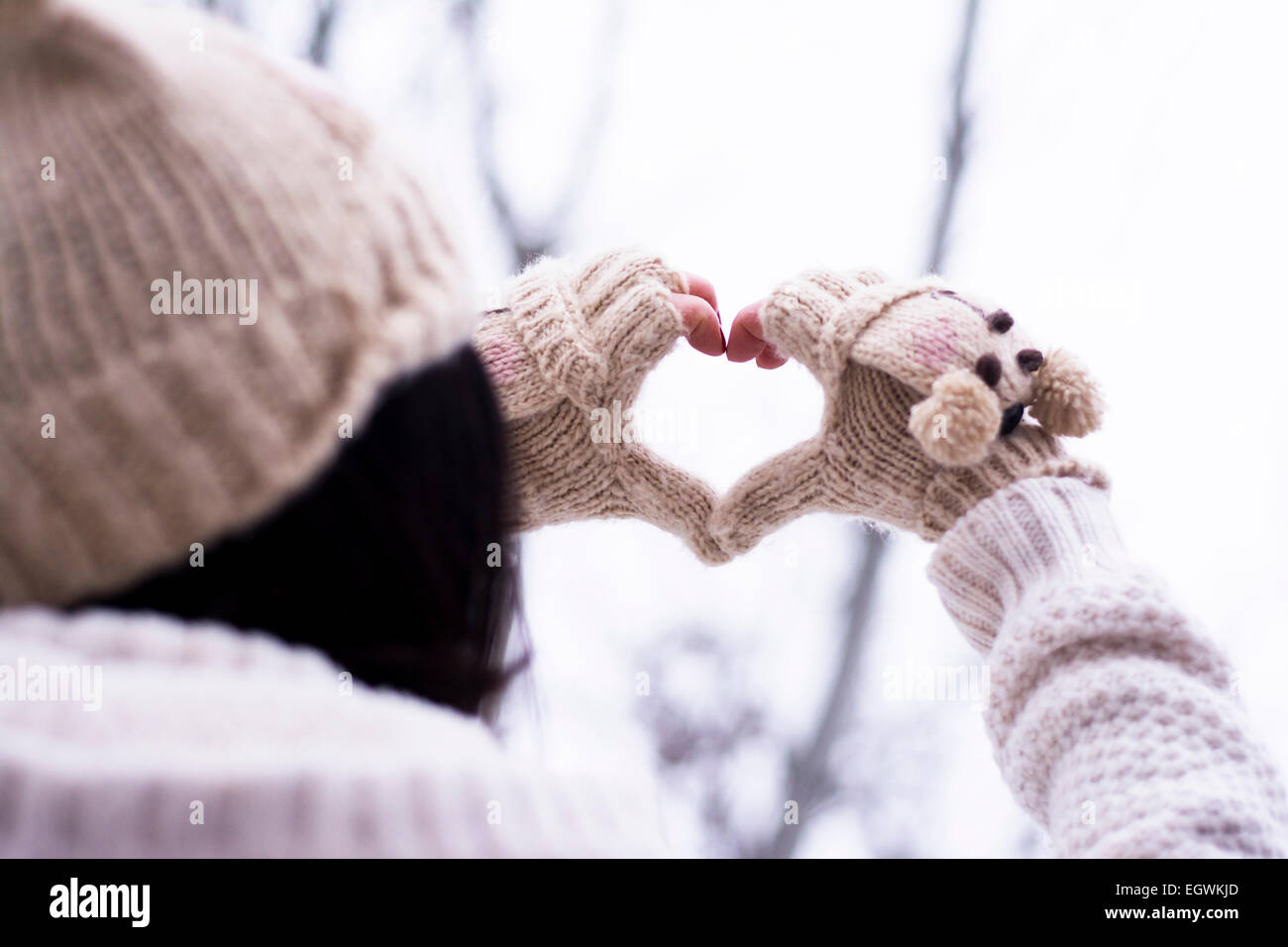 Woman making heart shape wearing knitwear gloves outdoors Stock Photo
