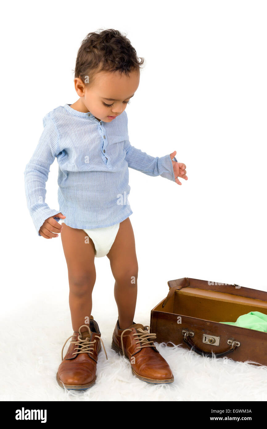 Playful African toddler boy having fun with Dad's shoes Stock Photo